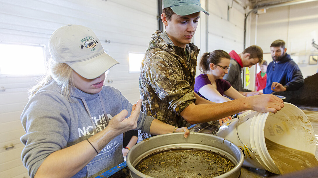 Shane Tucker (right), highway salvage paleontologist with the NU State Museum, directs the museum’s education interns in the process of wet screening for microfossils. The method is one of many used to search for specimens as part of the Highway Paleontology Program.