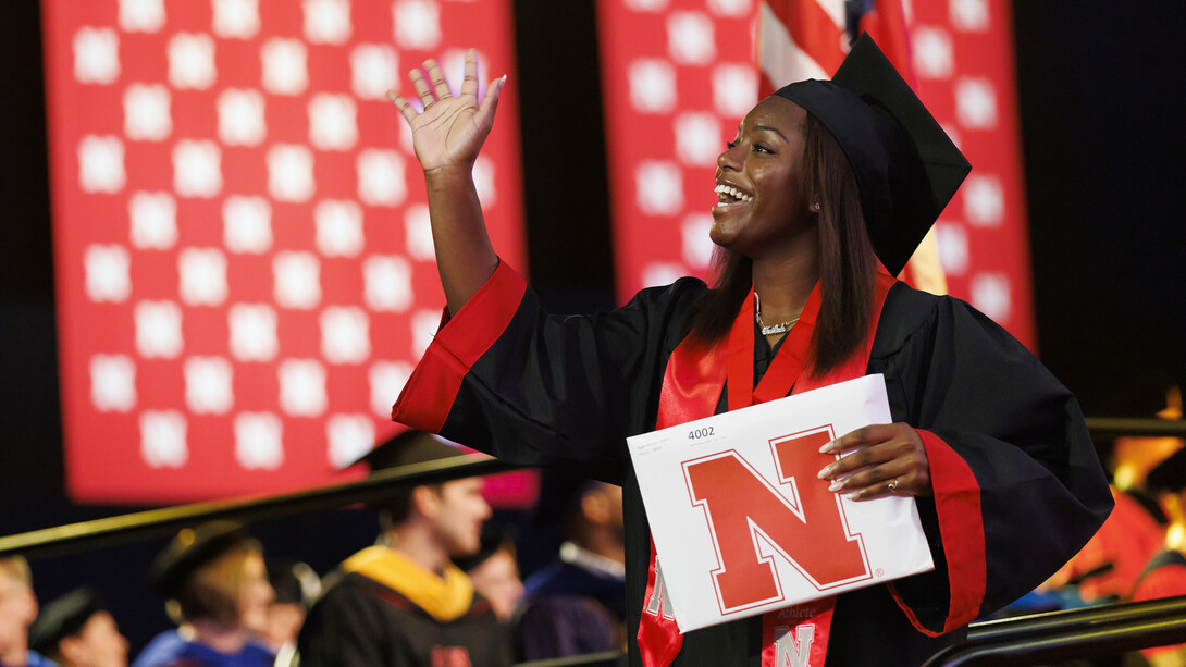 Nailah Dillard, dressed in graduation attire, waves to family and friends after receiving her degree during the combined graduate and undergraduate commencement ceremony Aug. 13 at Pinnacle Bank Arena. She earned a Bachelor of Science in Criminology and Criminal Justice.