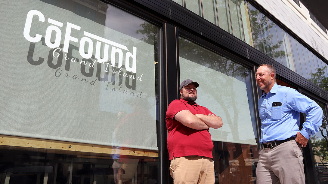 Shawn Kaskie (right) talks with Jonathan Rhoades in front of a glass storefront with the CoFound logo. CoFound is a collaborative workspace for tech entrepreneurs.