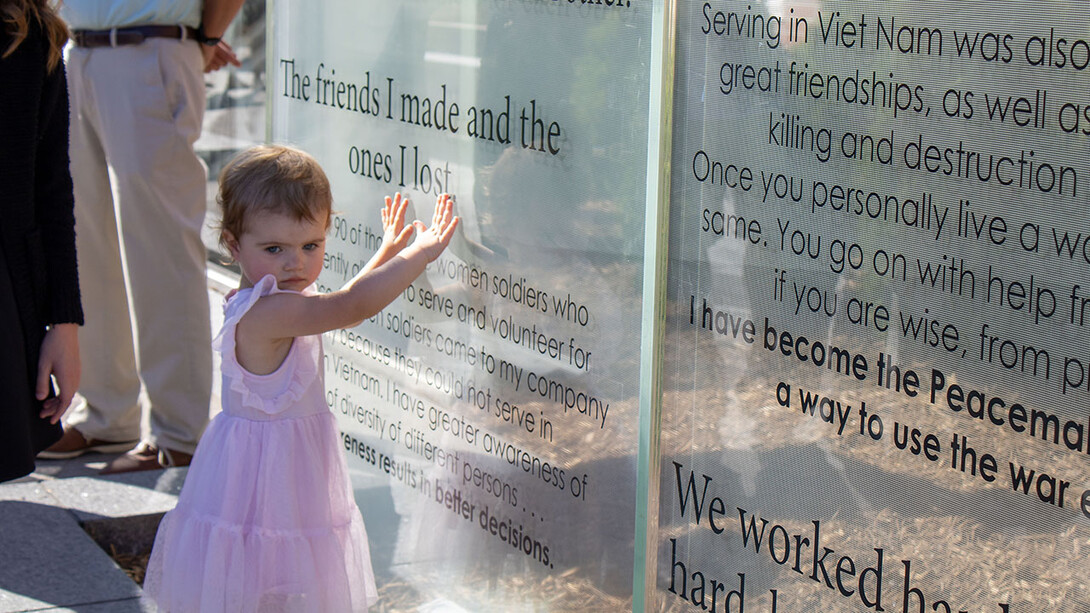 A young girl touches one of the glass panels of the new Veterans’ Tribute.