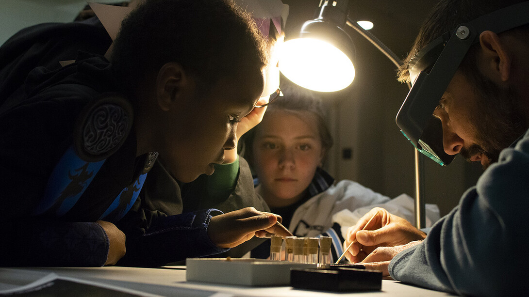 Shane Tucker (right), highway paleontologist with the University of Nebraska State Museum, shows visitors how microfossils are sorted during a previous Fossil Night event. 