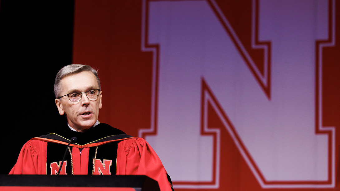 Chancellor Ronnie Green, dressed in his doctoral robe, stands behind the lectern at commencement.