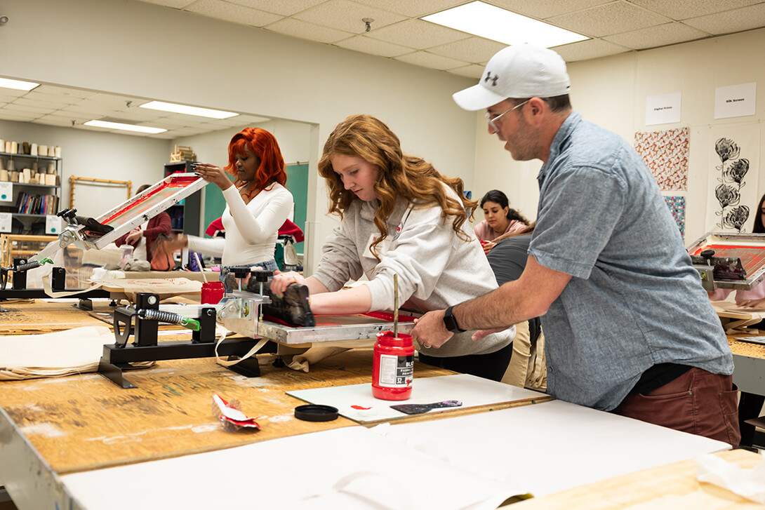 Michael Burton, assistant professor of art and design, assists a visiting high school student with a screen printing project during the TMFD Expo.