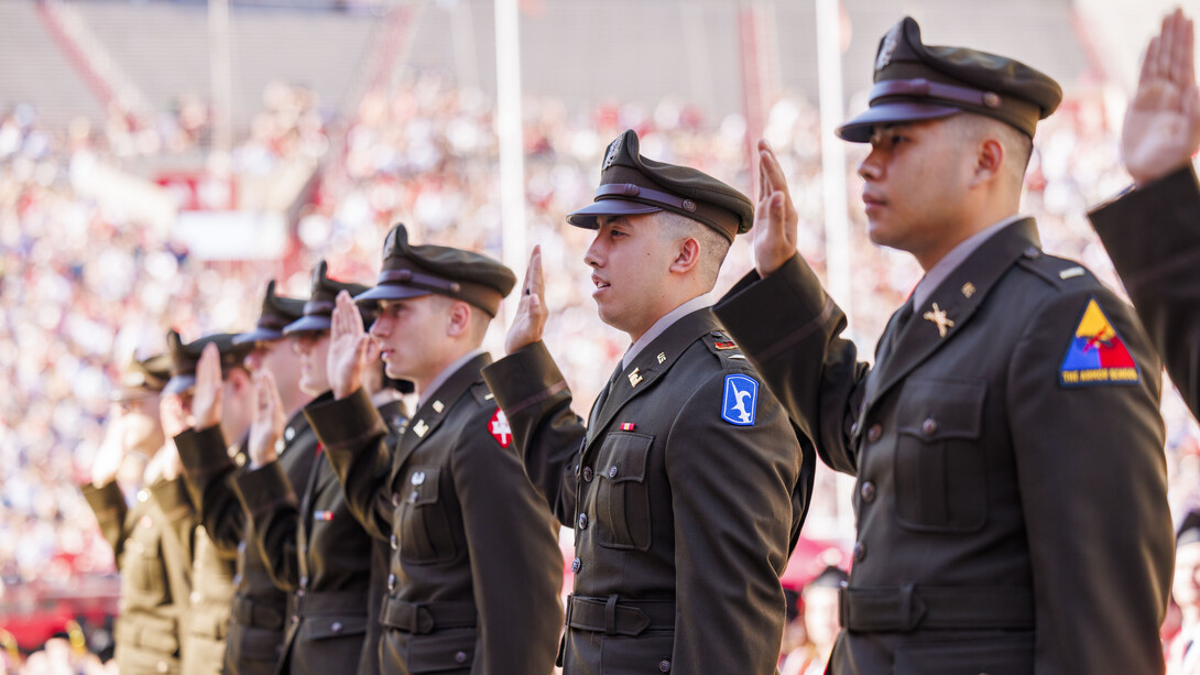 Air Force, Army and Naval ROTC members hold up their right hands as they recite the oath of enlistment at Memorial Stadium.
