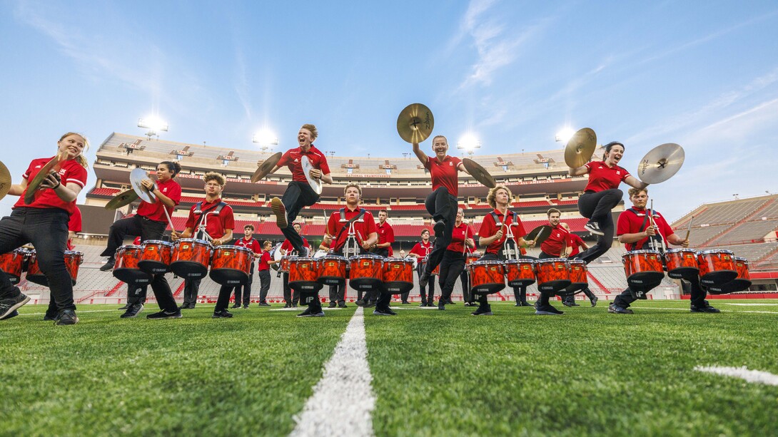 The Cornhusker Marching Band cymbal line jumps over the quad line during the battery’s individual performance during the Cornhusker Marching Band's annual exhibition concert Aug. 23 at Memorial Stadium.