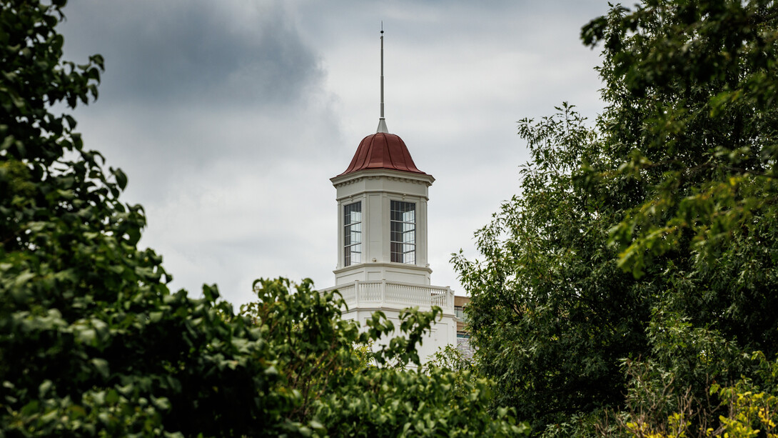 The Love Library cupola is visible through the trees on a cloudy day.