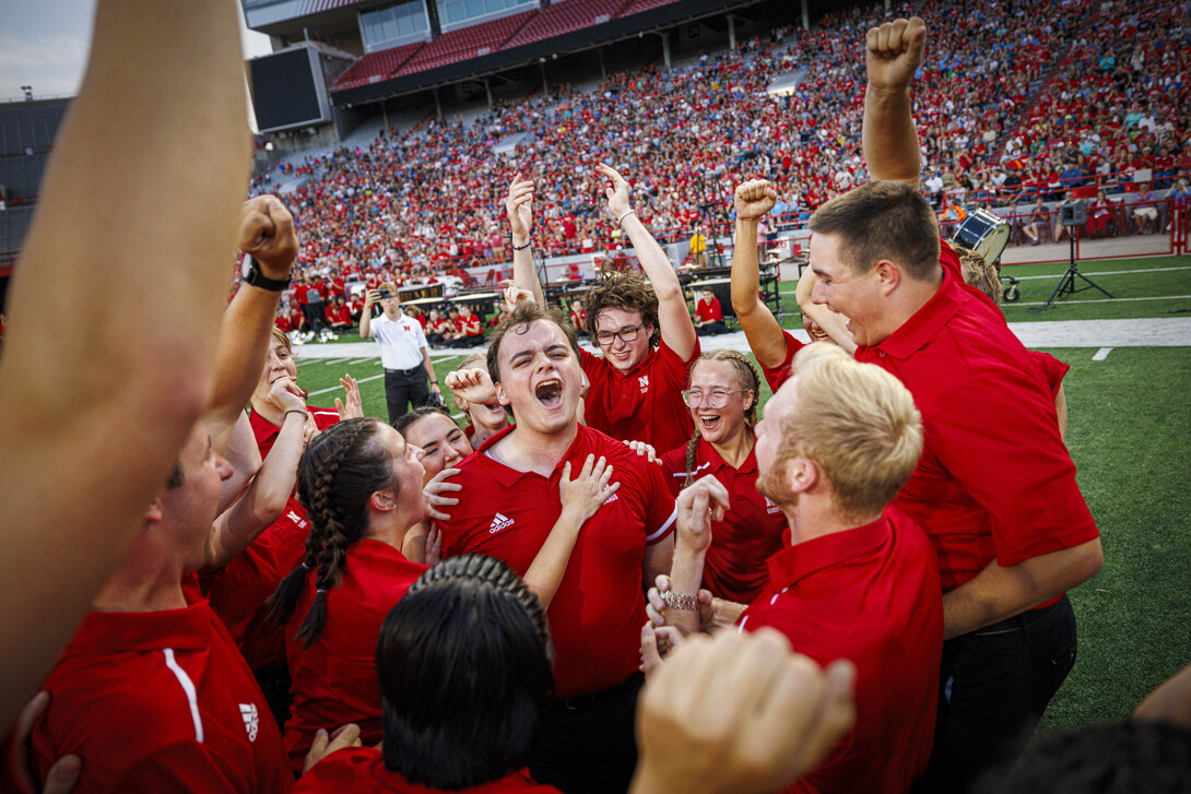 Luke Partsch is mobbed by his fellow mellophone players after winning the “drill down” competition during the Cornhusker Marching Band’s 2024 exhibition.