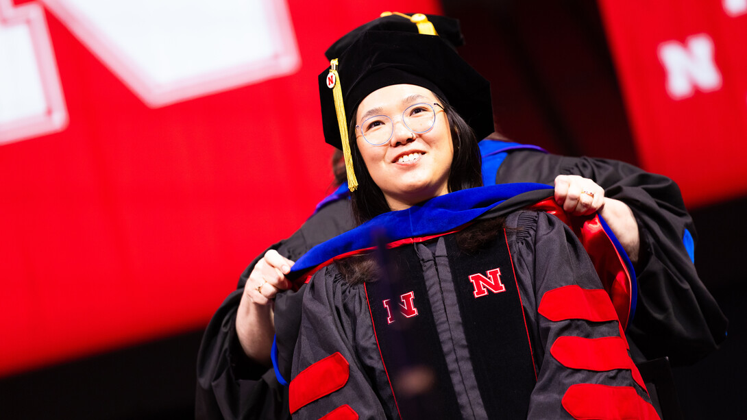 Justine Yeo smiles as she receives her doctoral hood during the combined graduate and undergraduate commencement ceremony Aug. 16 at Pinnacle Bank Arena.