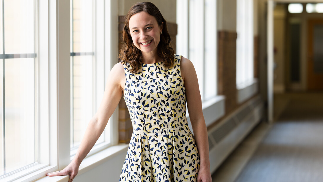 Jenna Finch, assistant professor of psychology, poses next to a window, with her right hand on the sill.