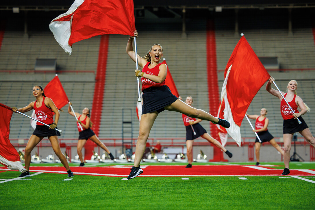 Color guard members jump with their flags in the section’s performance during the Cornhusker Marching Band’s annual exhibition concert Aug. 22 at Memorial Stadium.