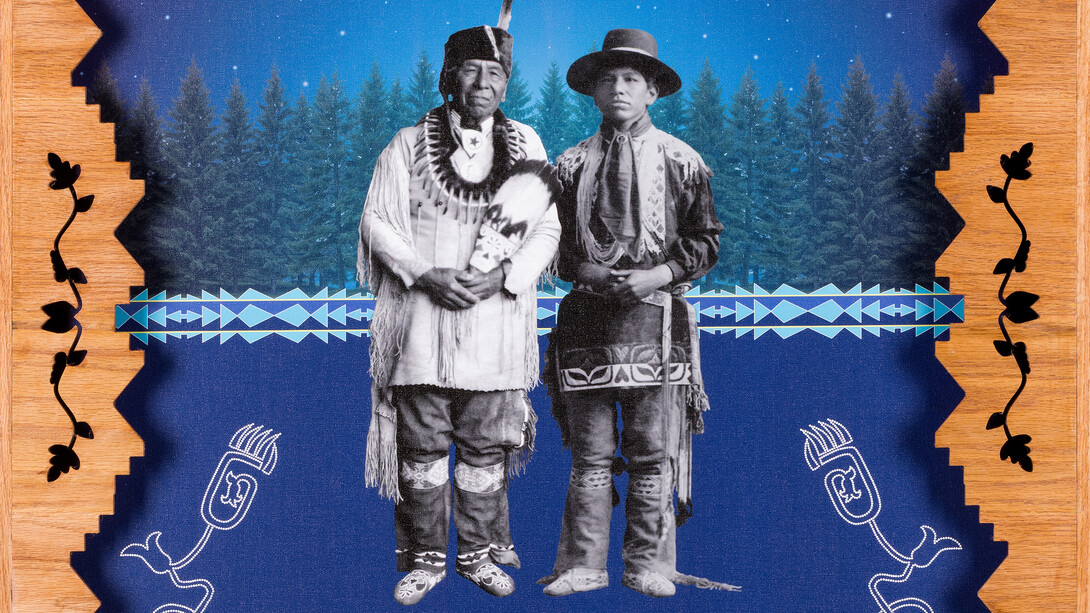 Two Native men stand in front of pine trees under a night sky in a digital media artwork with an elaborate wooden border.