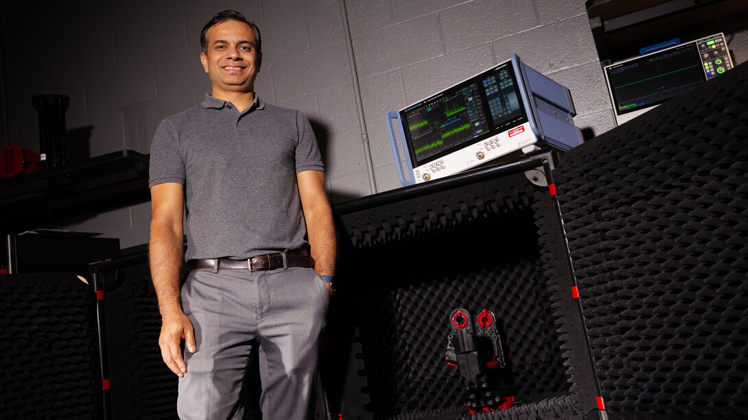 Shubhendu Bhardwaj, associate professor of electrical and computer engineering, poses in a lab  in front of a compact chamber lined with foam.