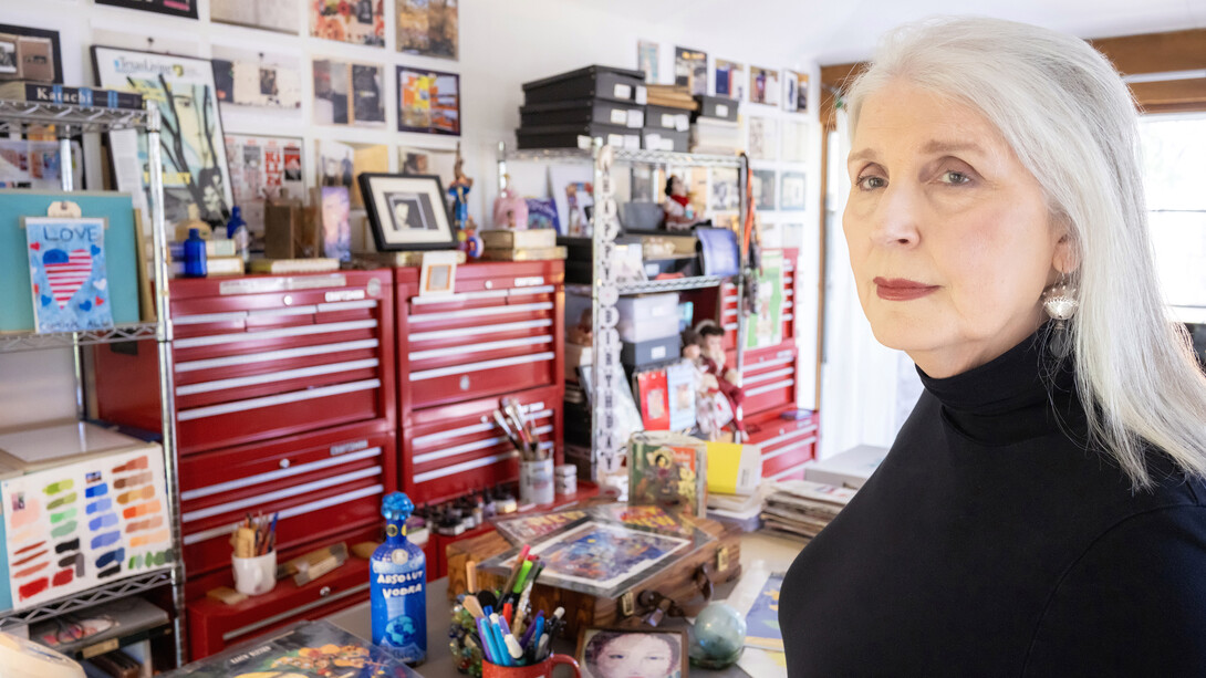 Artists Karen Blessen, wearing a black sweater, stands in an art workshop.