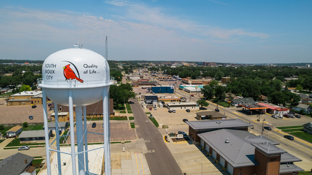 An aerial view of South Sioux City, showing a white water tower with a cardinal on it, a fire station, gas station and several other businesses.