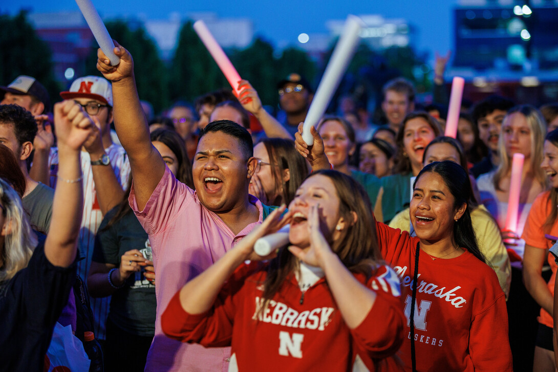 A crowd of young people cheer at an outdoor concert.