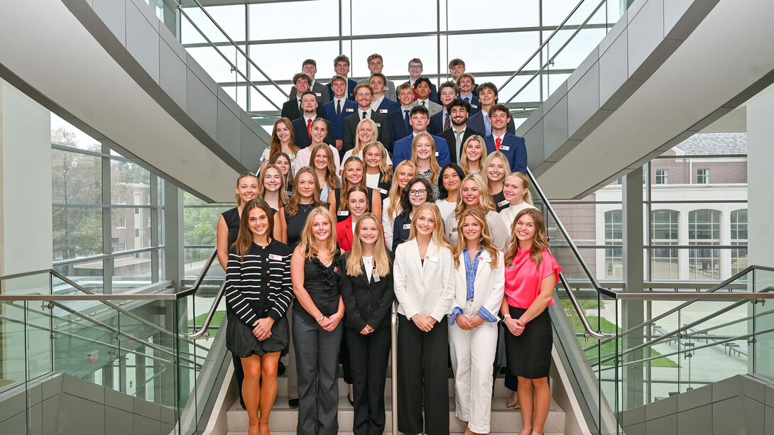 About 40 students in formal attire — all pursuing their undergraduate certificate in sales excellence from the University of Nebraska–Lincoln — stand on a staircase in Howard L. Hawks Hall.