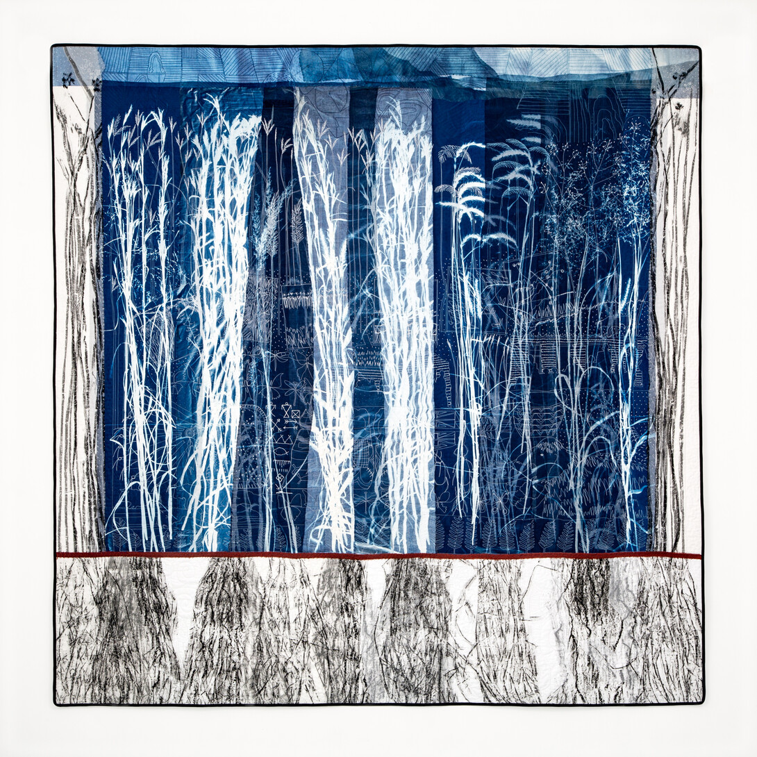 A quilt featuring cyanotype images of prairie grass and their roots.