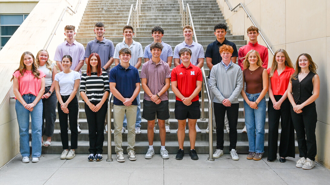 Eighteen students pose on a staircase outside Howard L. Hawks Hall.