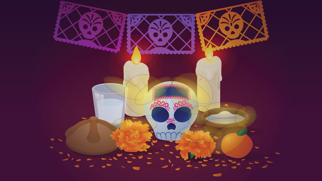 A home altar (or ofrenda) featuring a decorative skull, orange flowers, bowl, cup, bread, candles and paper cutouts.