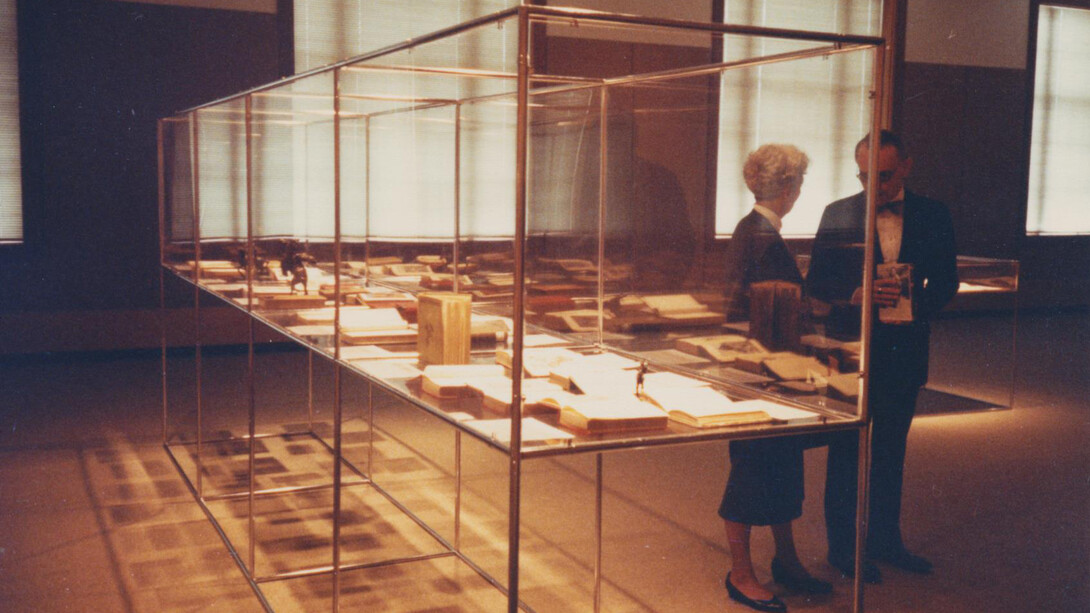 A man and woman stand next to a museum display case in Love Library.