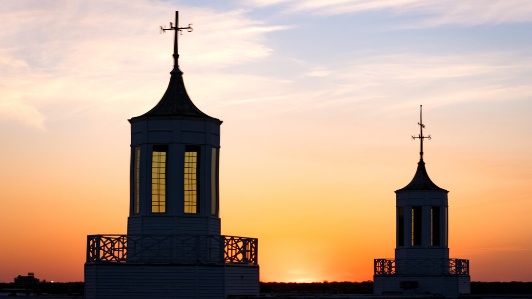 The sun rises behind the Love Library cupolas, seen in silhouette.
