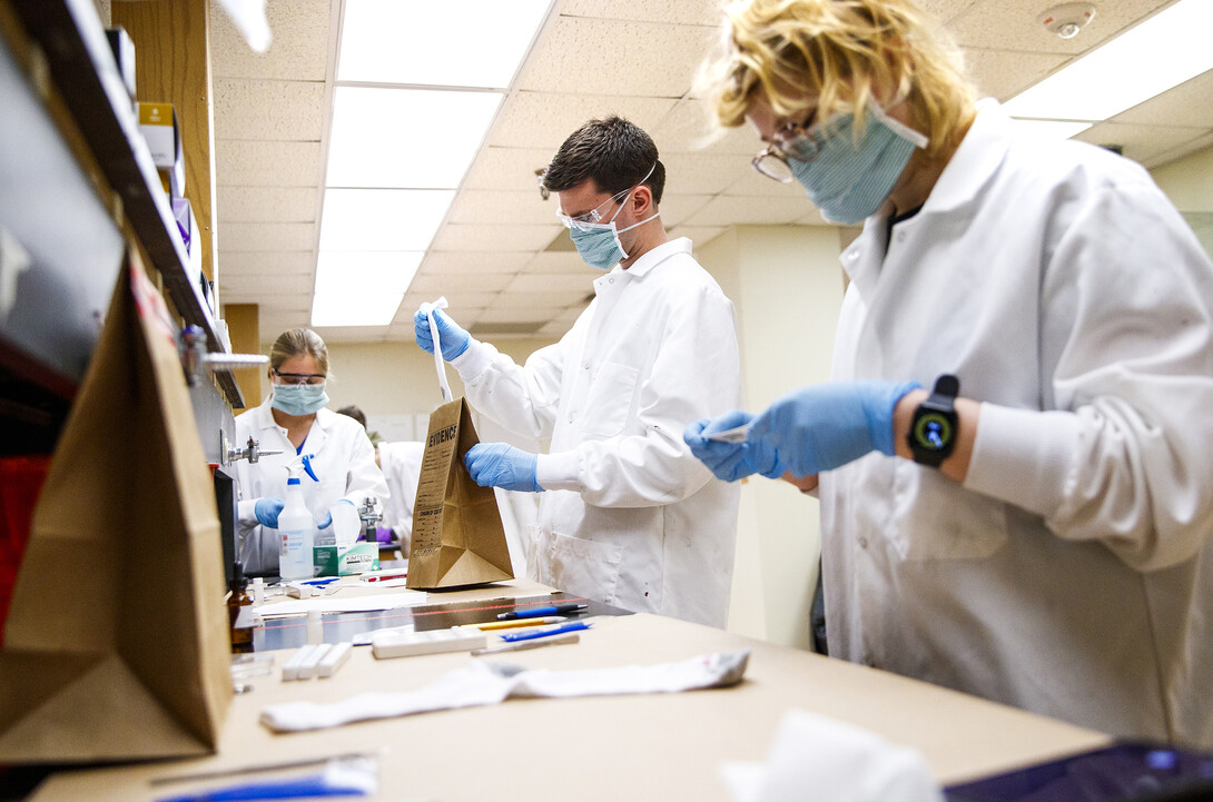 Brock Calamari removes a stained sock, which appears to be blood and will be tested. The work is part of the Forensic Science Capstone course, which brings together crime scene investigation, lab work and mock court testimony.