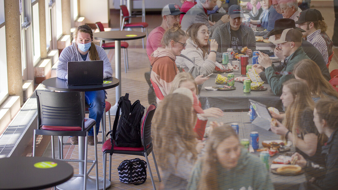 .Megan Eichhoff, a senior pre-veterinary medicine major, participates in an online class in the lobby of the Animal Science Complex on March 9. Nearly a year ago to the day, the space hosted a packed house CASNR Week event (shown on the right of this composite image).