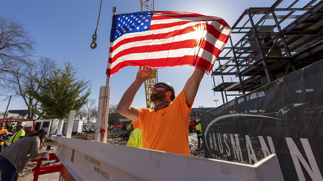 A Hausmann Construction employee unfurls a flag placed on the final steel beam during the topping out ceremony on April 9. The ceremony has roots to an ancient Scandinavian tradition that, in modern times, signals the completion of the internal structure of a building.