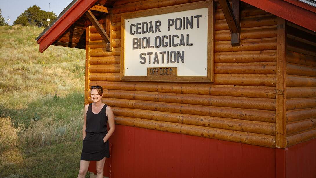 Sarah Kaizar stands next the cabin-like office at Cedar Point Biological Station. 