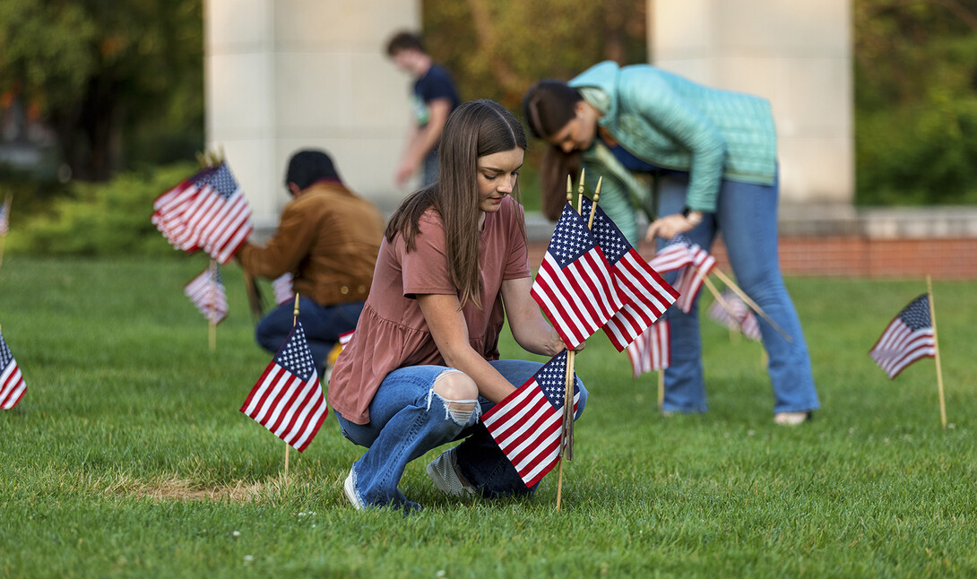 Madu Hadley places a flag in the ground north of the Nebraska Union on Sept. 9, 2021.