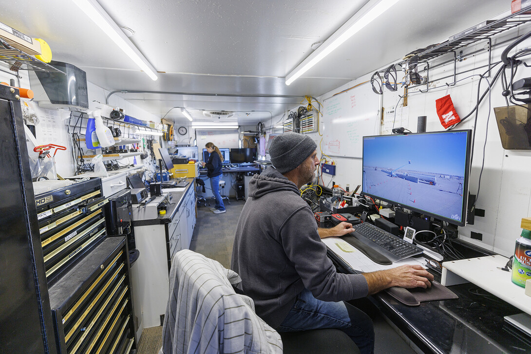Jim Holloway and Karla Lechtenberg work on the computer connections and camera views in a trailer rigged to record the information at the crash test site. The test was Dec. 8 at the Midwest Roadside Safety Facility’s Outdoor Proving Grounds on the western edge of the Lincoln Municipal Airport. 