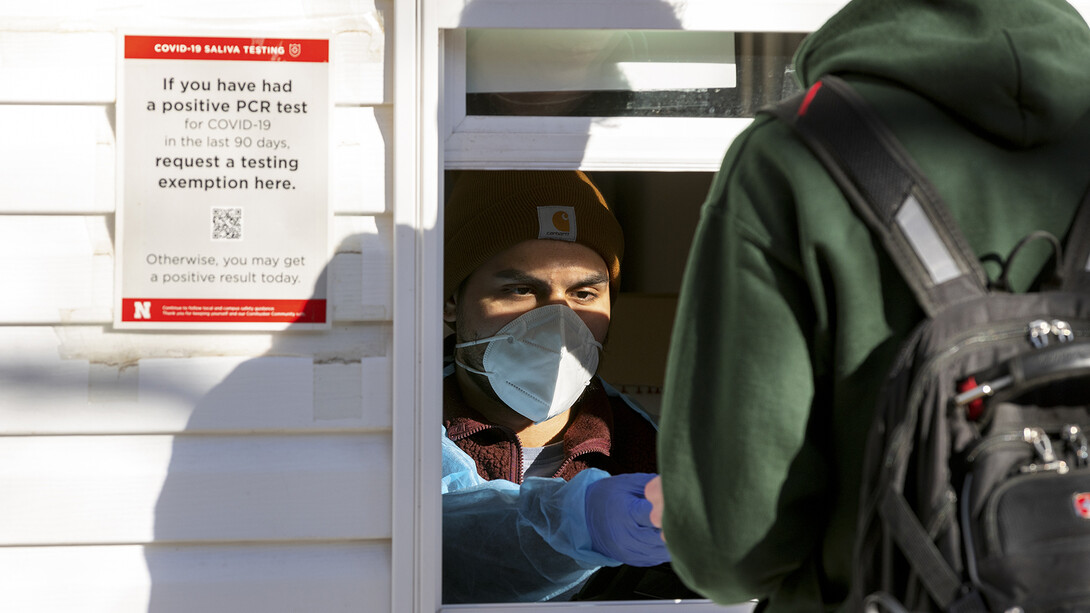 A student delivers a vial of saliva at the Nebraska Union COVID-19 test location on Jan. 18. All students, faculty and staff are going through re-entry testing at the start of the spring semester. The testing system will shift to focus on residence halls and Greek houses next week.