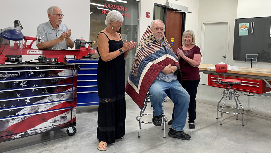 Doug Karaoke, Pat Young and Victoria Young applaud Jim following the wrapping of the quilt at Nebraska Innovation Studio July 29.