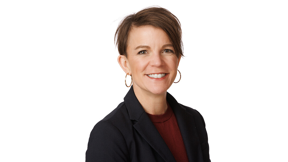 Valerie Jones, wearing a black blazer, is photographed on a white background.