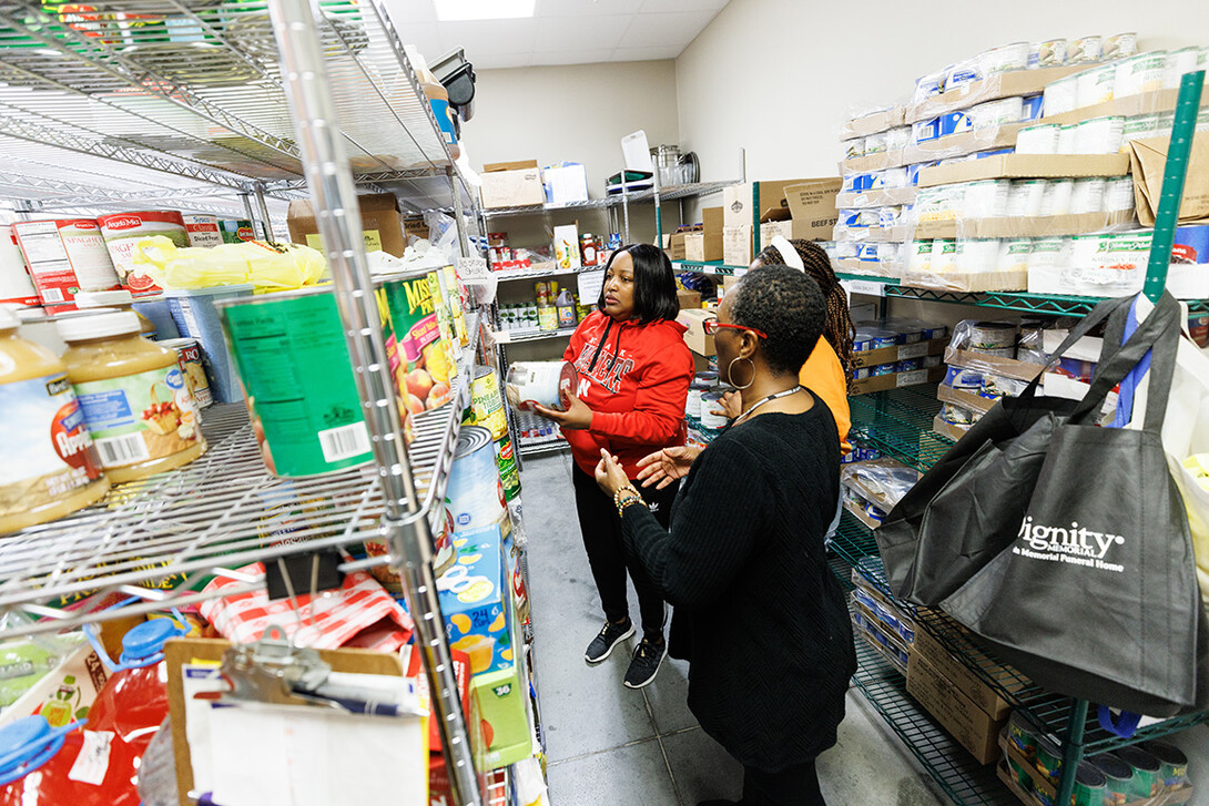 Trish Manga, in red, Maryam Sule, and Falesa Ivory, right, sort food for neighborhood groups in the storeroom.