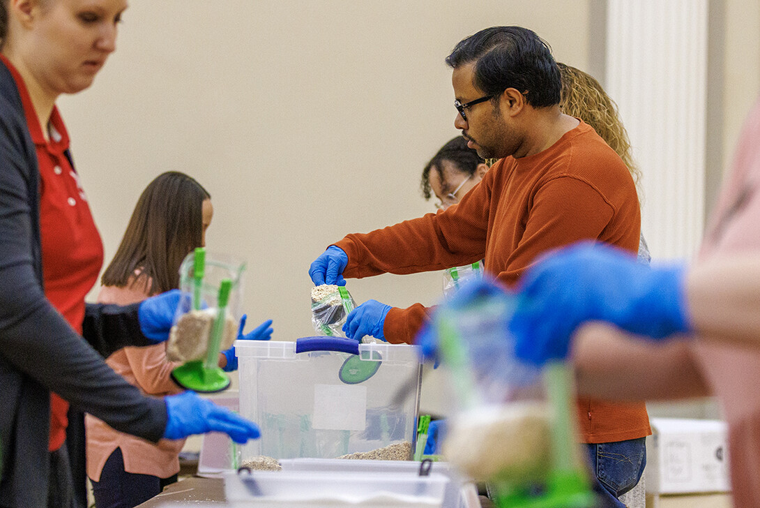 Arindam Malakar, research assistant professor with the Nebraska Water Center, scoops oatmeal into bags. The volunteers assembled 2,350 servings of oatmeal.