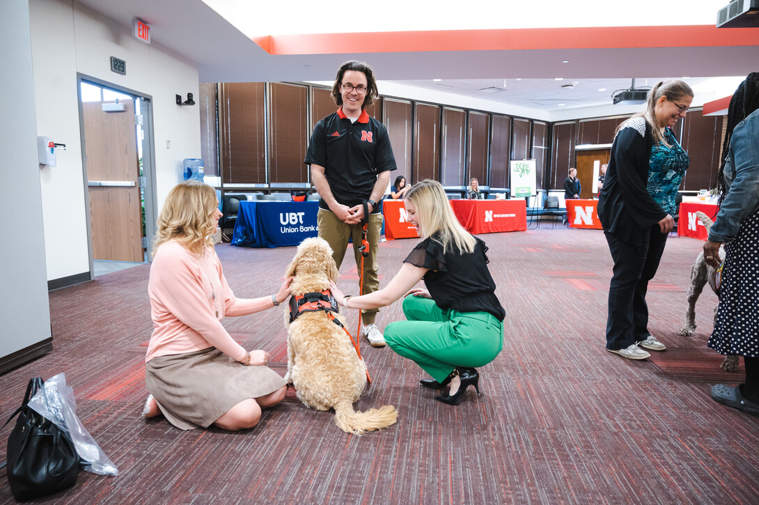 Photo Credit: Garrett Stolz // Brett Neely smiles for a photo as Marko receives some attention from Huskers during a Pawp Up event on campus.