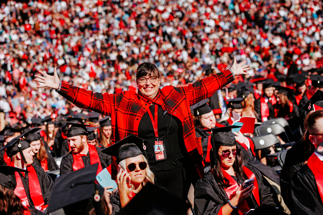Annette Wetzel smiles for a photo with her arms outstretched in a sea of Husker grads before undergraduate commencement