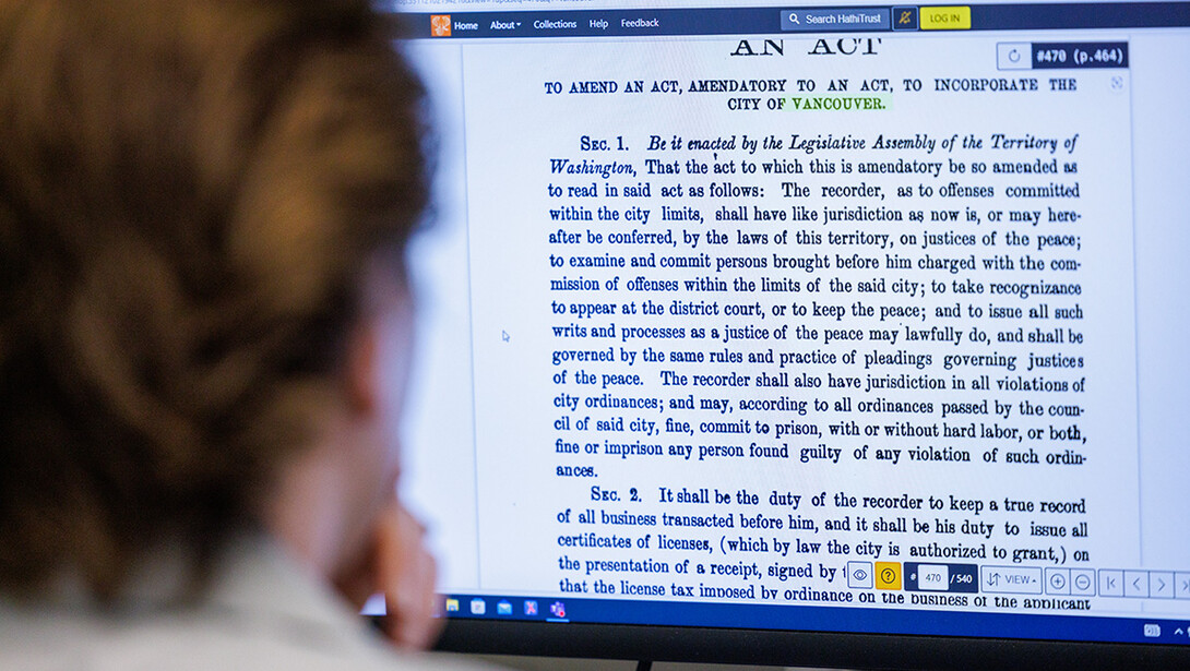 A historical document is on a computer screen, with the head of a student in the foreground. Students transcribed these documents for a digital humanities research project.
