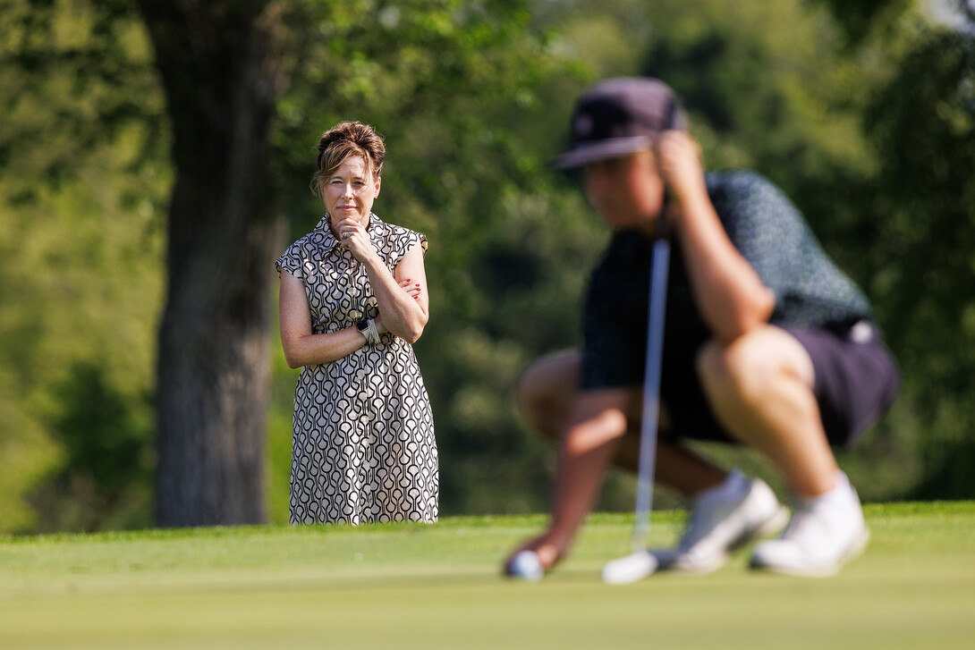 Tiffany Heng-Moss watches her son prepare to putt.