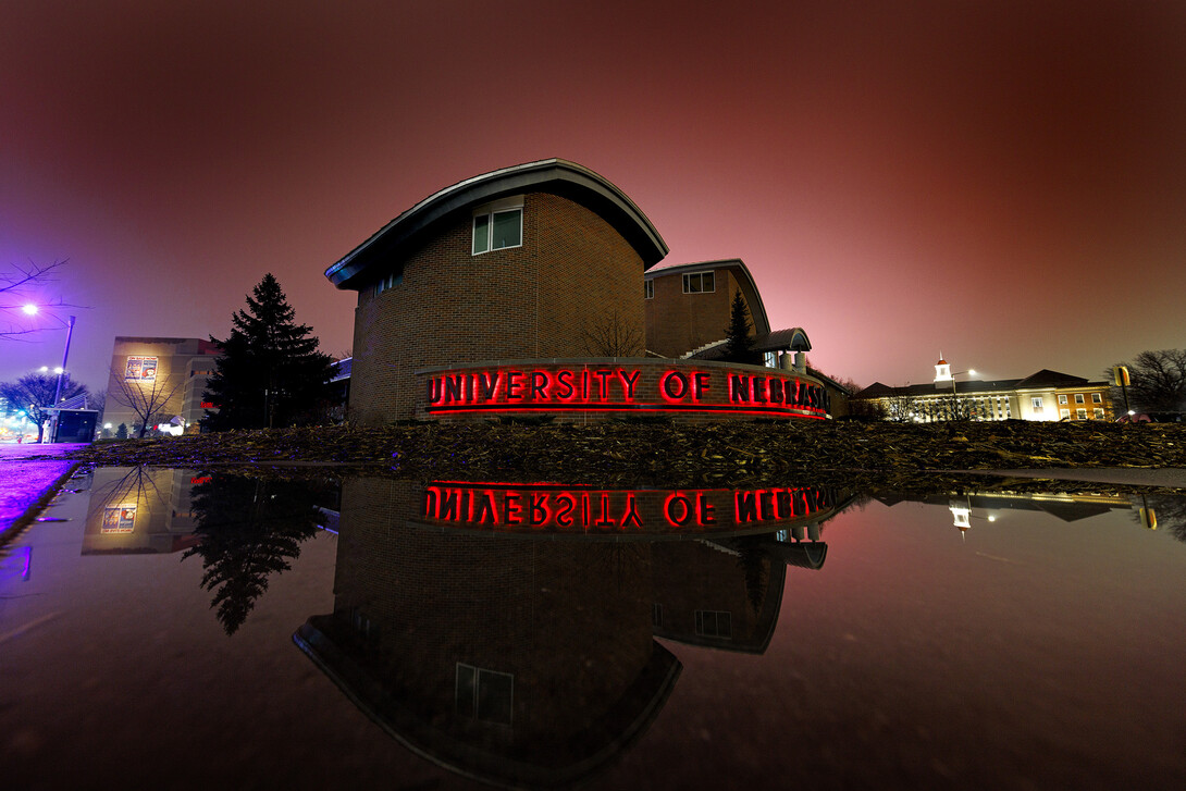 Dusk illuminates the Campus Visitors Center following rains, which reflect the welcome sign.