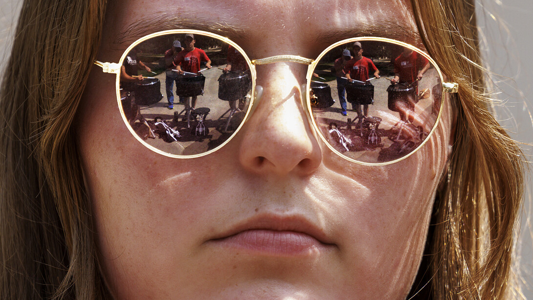 Avryn Schardt’s sunglasses reflect the marching band snares as they practice in the Sheldon Sculpture Garden on Aug. 15.