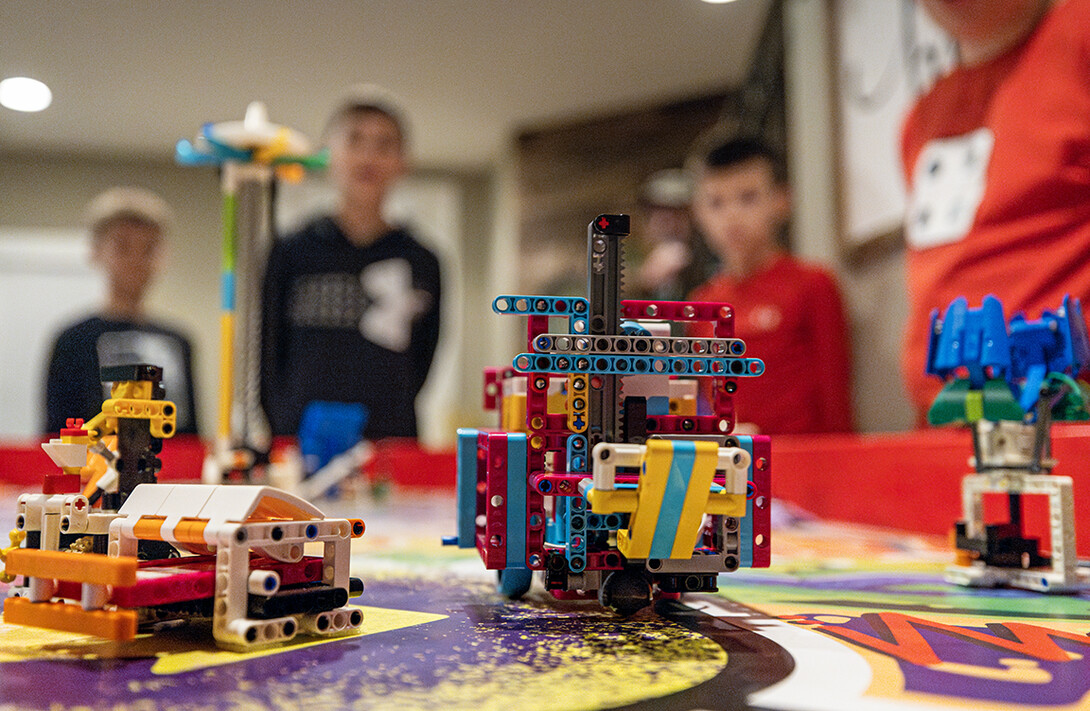Robots made from Lego bricks sit on a FIRST LEGO League game board.