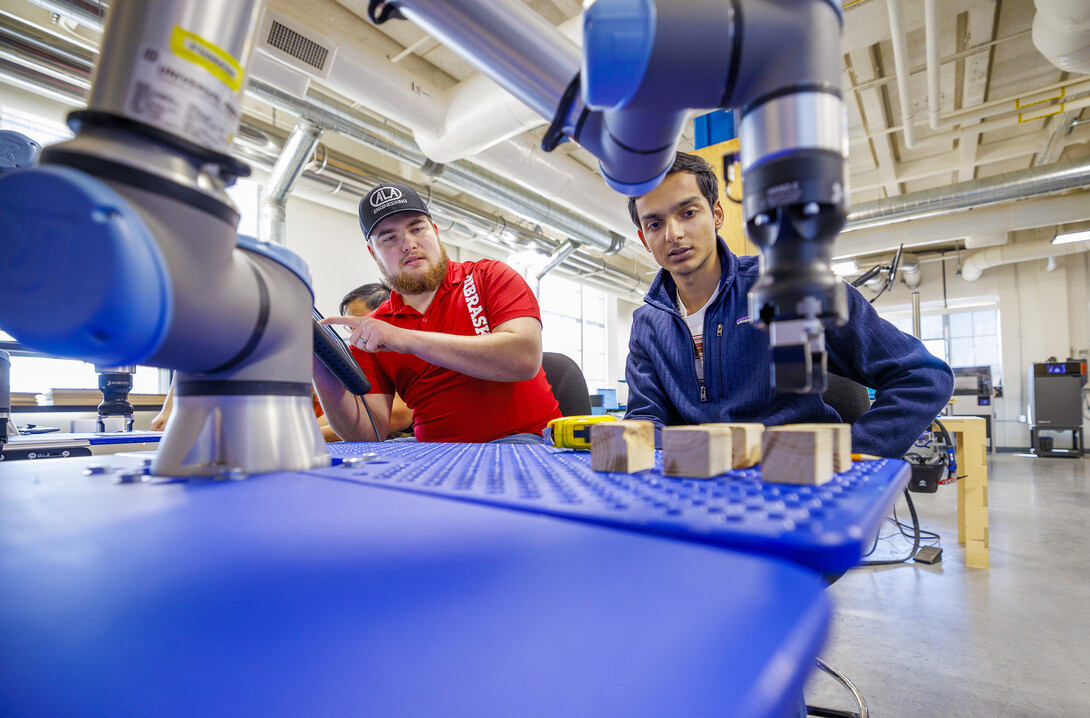 Jacob Hansen, with ALA engineering and a Nebraska alumni, and Kunjan Theo Joseph with the UNL MAARS Lab, work at making their robotic arm program stack blocks.  The programming would simulate a larger robotic arm stacking pallets. Nebraska Innovation Studios is working with robotic arms and teaching students and local industry people how to use them.