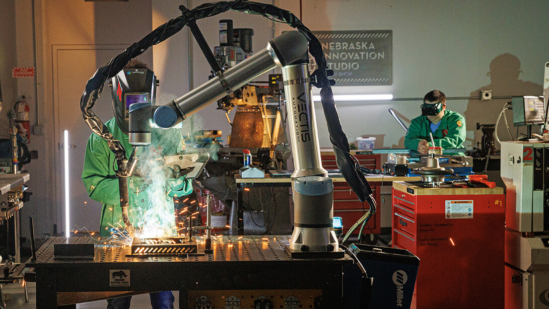 A Nebraska Innovation Studio member guides a welding robot in the metal shop. 