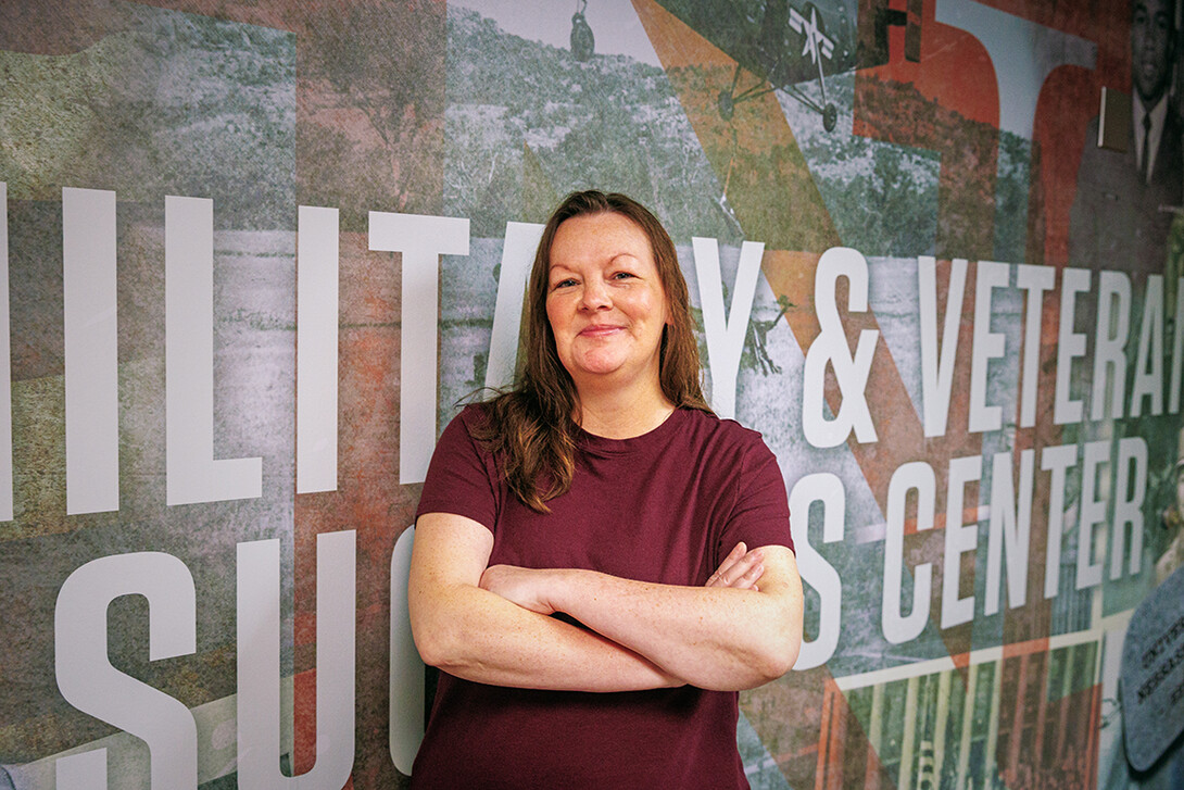 A woman stands in front of a mural.