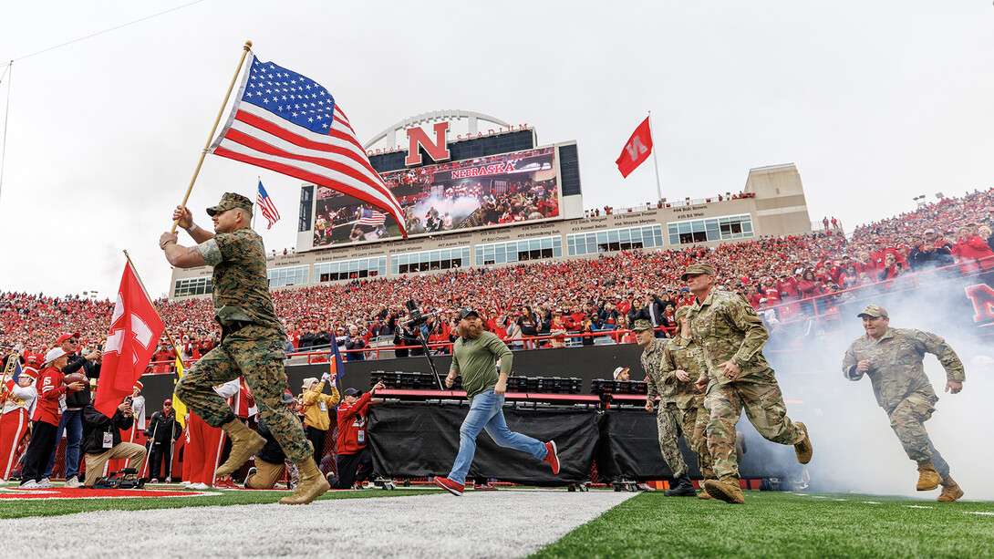 Dylon Taylor, U.S. Marine, leads soldiers and the Husker football team onto the field ahead of the Nov. 1 game with UCLA>