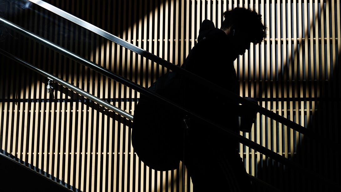 A student, silhouetted by the warm glow of fall sunlight on the wall behind, quietly descends stairs in Howard Hawks Hall on Nov. 12. 