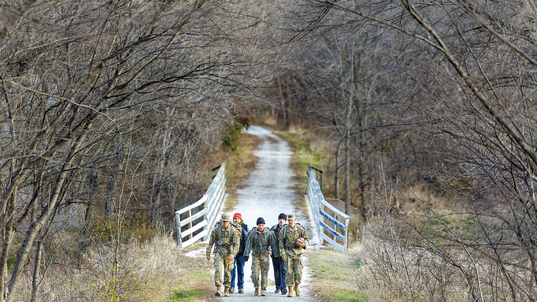 Ruck March participants walk along a rural Saunders County bike path as they transport a ceremonial game ball to campus as part of the 2024 Ruck March.