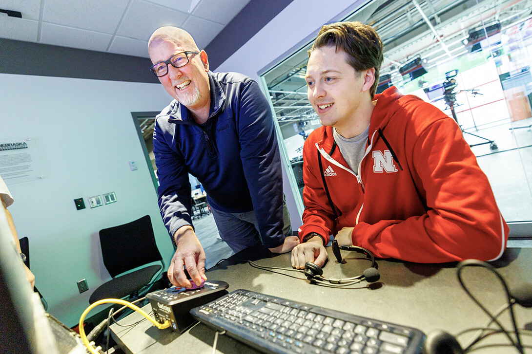 Jamie Wenz, technical director in the College of Journalism & Mass Communications, left, assists Harmon Johnsen, sophomore, inside the Don and Lorena Meier Studio.